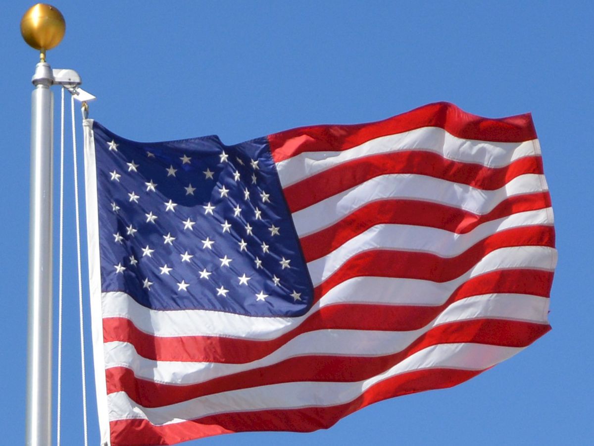 This image shows the flag of the United States of America, with stars and stripes, waving on a flagpole.